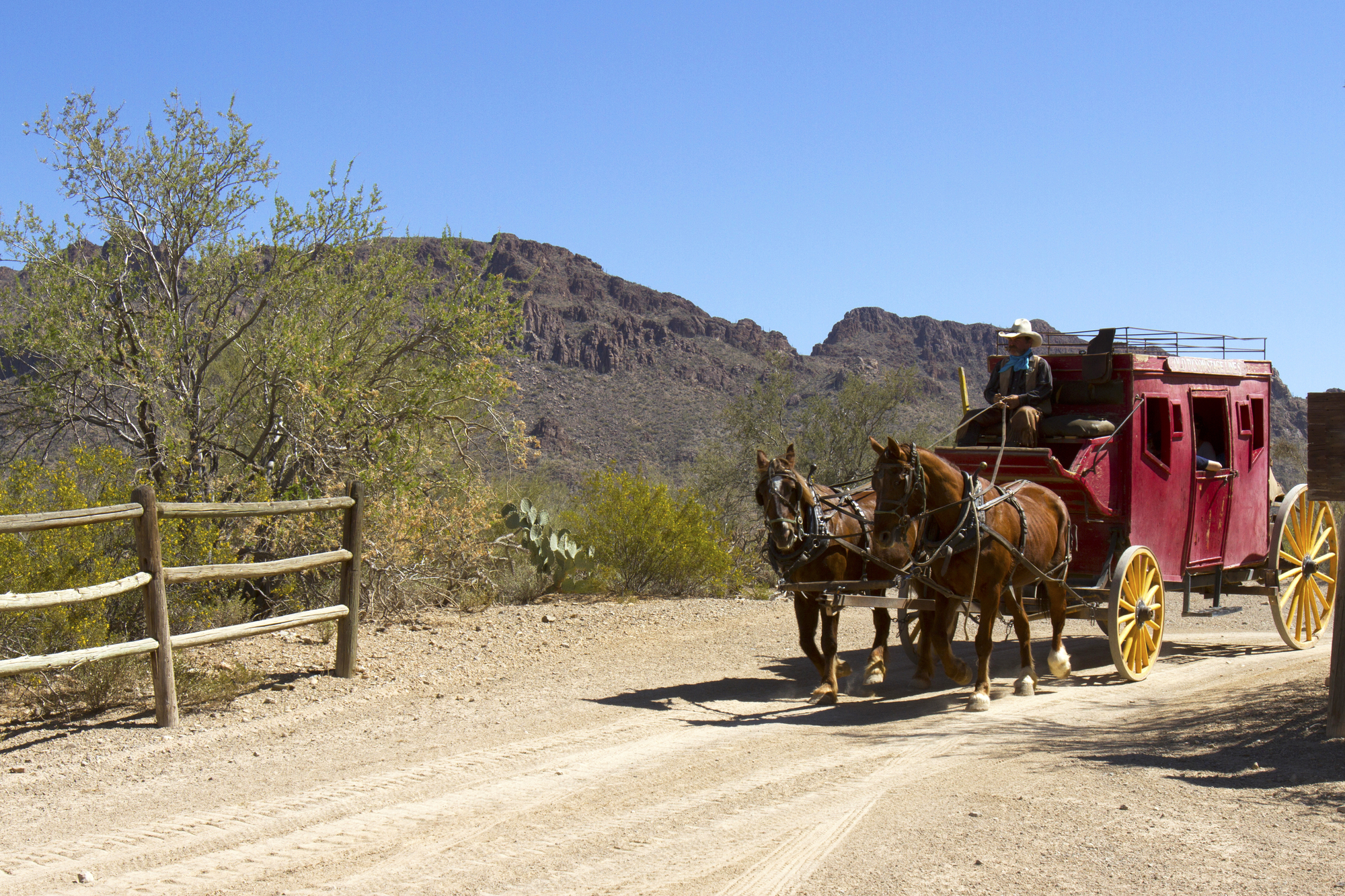 Team of horses pulling stage coach through desert in american southwest